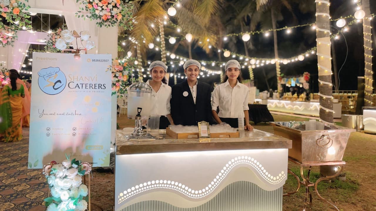 Shanvi Caterers staff serving at an outdoor night event with fairy lights